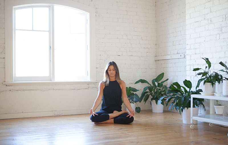 woman meditating in minimalist yoga studio